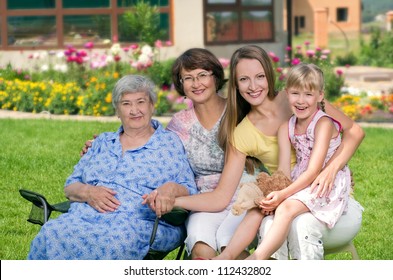 Four Generations Of Women Sitting Together At Countryside And Smiling