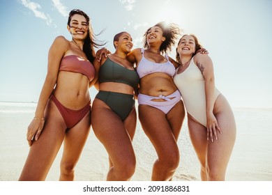 Four girlfriends enjoying beach day together. Group of cheerful young women embracing each other while wearing swimwear. Carefree female friends having fun during their summer vacation. - Powered by Shutterstock