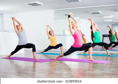 Four girls practicing yoga, Yoga - Virabhadrasana/Warrior pose - Powered by Shutterstock