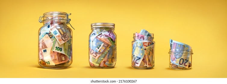 Four glass jars with savings, cash money (euro banknotes) banknotes) on yellow background