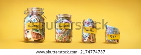 Four glass jars for savings, cash money (euro banknotes) on yellow background. For utility bills: heating, electricity, water. Savings for life and food
