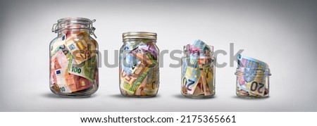 Four glass jars with savings, cash money (euro banknotes) on grey background