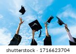 Four graduates throwing graduation hats in the air.