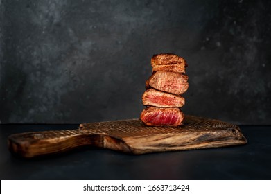 
Four Grilled Steaks With Spices On A Stone Background. Four Types Of Meat Frying Rare, Medium, Medium Well, Well Done