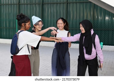 Four group young attractive Asian multi ethnic woman friends colleagues students talk walk discuss mingle outdoors backpack handphone holding hand together playing fun
