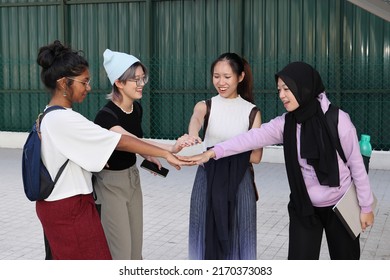 Four group young attractive Asian multi ethnic woman friends colleagues students talk walk discuss mingle outdoors backpack handphone holding hand together