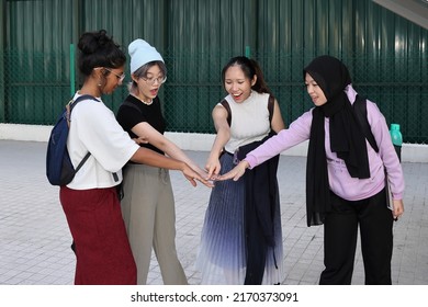 Four group young attractive Asian multi ethnic woman friends colleagues students talk walk discuss mingle outdoors backpack handphone holding hand together