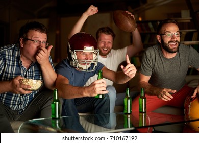 Four Guys Cheering In Front Of TV While Watching American Football Game