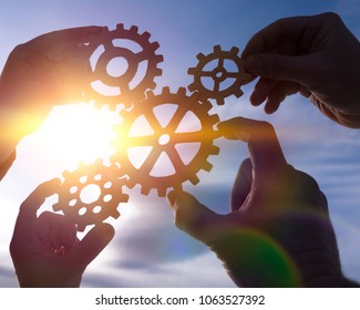 Four hands of businessmen collect the gear from the gears of the details of the puzzles. against the background of sunlight. Concept business idea. Teamwork, cooperation, strategy - Shutterstock ID 1063527392