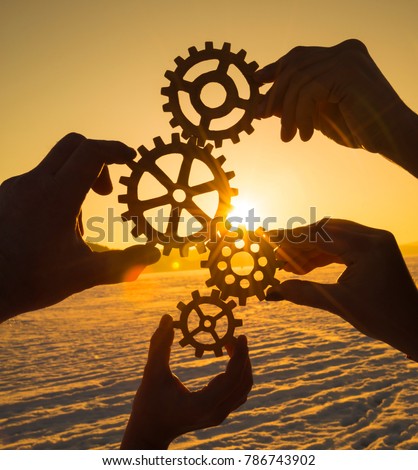 Four hands collect the gear from the gears of the details of the puzzles. against the background of sunlight. Concept business idea. Teamwork