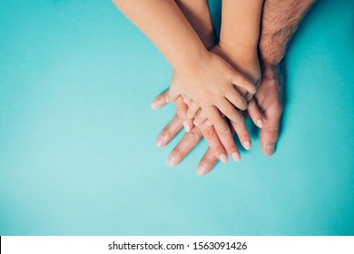 Four hands on blue background. Dad, mom, daughter and little son put their hands on each other. Family, friendship, love, heritage concept - Shutterstock ID 1563091426