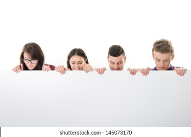 Four Handsome Young People Isolated On White Looking Down A Blank Sign