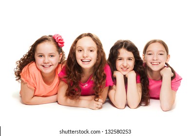 Four happy amazing 10 years old girls in pink laying on the floor, isolated on white