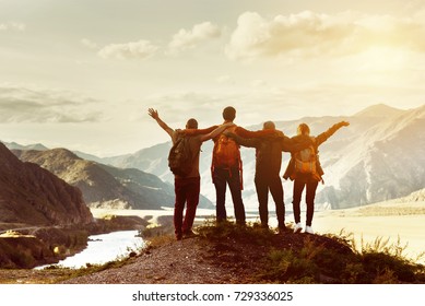 Four happy friends are looking on mountains and having fun together. Space for text. Travel concept
