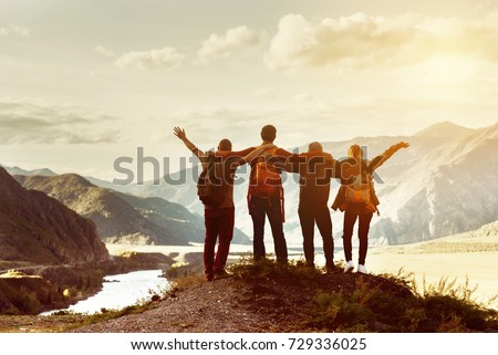 Four happy friends are looking on mountains and having fun together. Space for text. Travel concept