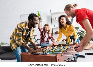 Four happy and joyful multiethnic friends playing table football in living room - Powered by Shutterstock