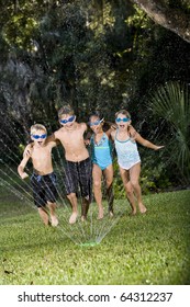 Four Happy Kids Running Arm In Arm Shouting And Laughing, Soaked By Lawn Sprinkler, Ages 7 To 9 Years