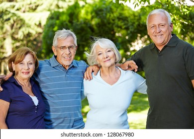 Four happy semiling senior people standing in nature in summer