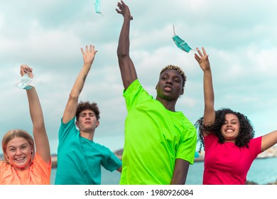 Four happy teenager  outdoors without medical mask with opened arms looking at the camera after quarentine and after passed the coronavirus or covid-19 - no more mask. Focus on black boy.