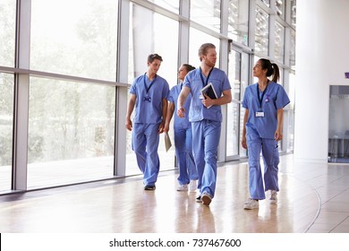 Four healthcare workers in scrubs walking in corridor - Powered by Shutterstock