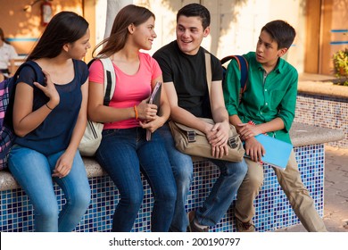 Four high school friends with backpacks and books hanging out after school