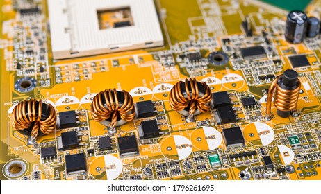 Four inductors with ferromagnetic core on circuit board of computer mainboard. Electrical components. Toroidal and cylindrical induction coils with copper wire winding. Surface mount technology. Tech.