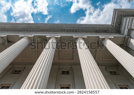 Four Ionic columns line the Treasury Building facade beneath blue cloudy sky.