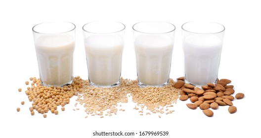 Four Kinds Of Vegetable Milk In Glass With Ingredients: Soy, Rice, Oat And Almond On White Background.