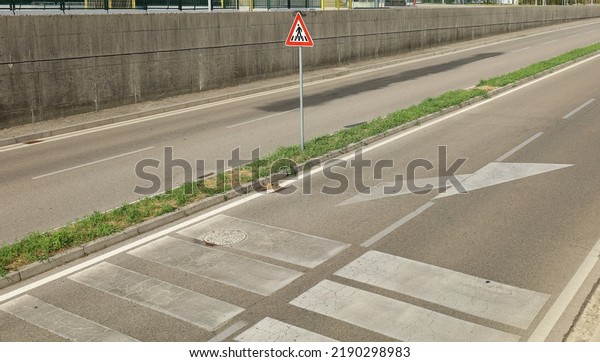 Four lane road with a pedestrian crossing warning\
sign in the traffic island. Concrete walls by sides. Background for\
copy space.