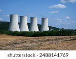 Four large nuclear power plant cooling towers releasing steam into the atmosphere.