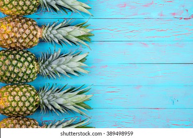 Four large ripe pineapples neatly arranged in row with copy space over wooden background in tropical theme - Powered by Shutterstock