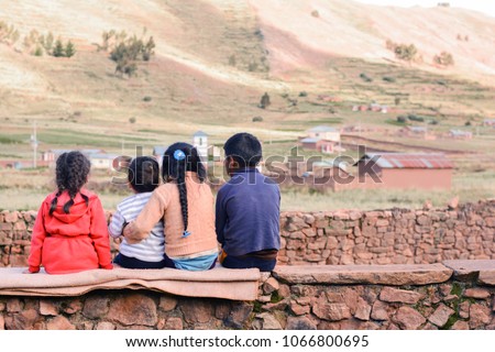 Four latin kids sitting on the wall and admiring a beauty of the nature.
