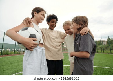 Four laughing intercultural friends standing in front of each other after game of soccer and having chat while enjoying rest after play - Powered by Shutterstock