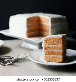 Four Layer Peach Cake With Vanilla Frosting On A Square White Cake Plate.  