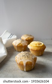 Four Lemon Poppy Seed Muffins On A Concrete Worktop With Dark Shadows.