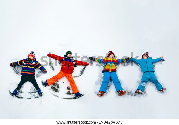Four little kid boys in colorful winter clothes\
making snow angel, laying down on snow. Active outdoors leisure\
with children in winter. Happy friends with warm hat, gloves,\
winter fashion