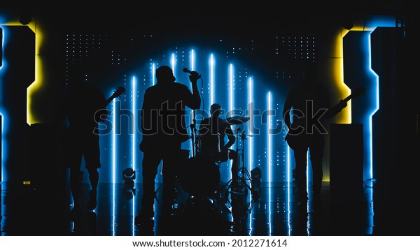 Four Man
Rock Band with Lead Singer, Guitarists, Bassist and Drummer
Performing at a Concert in a Night Club. Live Music Party in Front
of Bright Colorful Strobing Lights on
Stage.