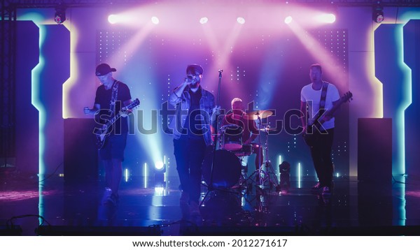 Four Man\
Rock Band with Lead Singer, Guitarists, Bassist and Drummer\
Performing at a Concert in a Night Club. Live Music Party in Front\
of Bright Colorful Strobing Lights on\
Stage.