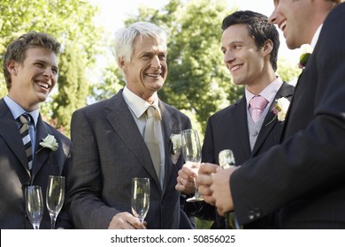 Four men holding empty wineglasses, smiling