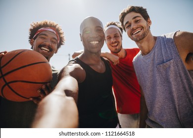 Four men posing for selfie holding a basketball. Smiling athletes enjoying while playing basketball. - Powered by Shutterstock