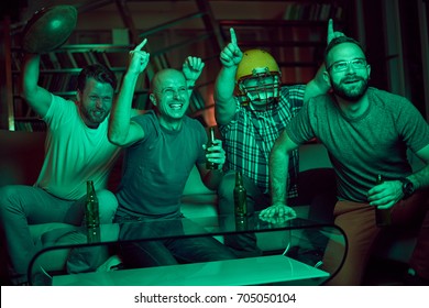 Four Men Watching American Football On Television, Dark Room, Light Coming Only From TV