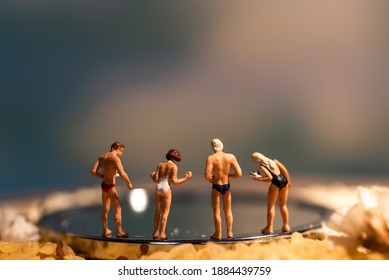 Four Miniature Figures Gather Around The Swimming Pool.