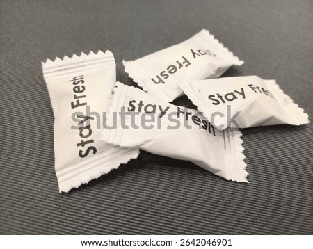 Four mints wrapped in white are placed on a table with a gray tablecloth.