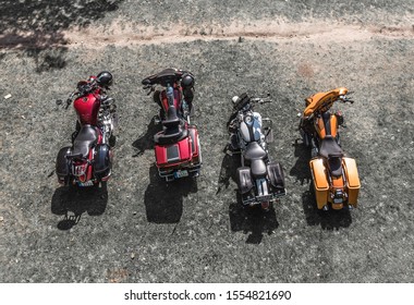 four motorcycles parked side by side on a gravel surface