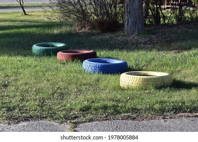 Four Multicolored Tires Lined Up On Grass.  