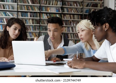 Four Multiethnic Schoolmates Look At Laptop Discuss Online Task, Learning Use Internet Resources, Search Information Busy In Studying Sit At Table In University Library. Higher Education, Tech Concept