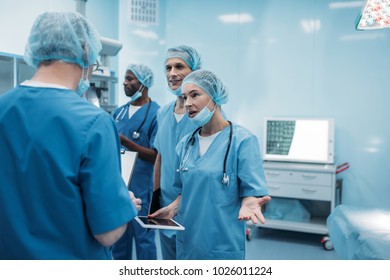 Four Multiethnic Surgeons Talking In Operating Room