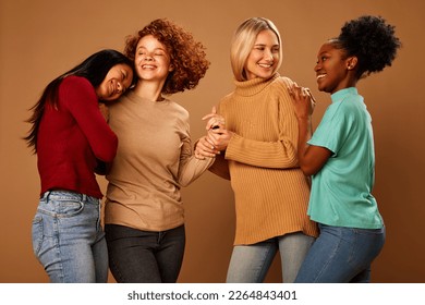 Four multiracial female friends hugging and laughing in studio isolated on brown background. - Powered by Shutterstock