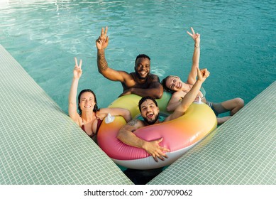 Four multiracial friends with a float in the pool, having fun in summer. - Powered by Shutterstock