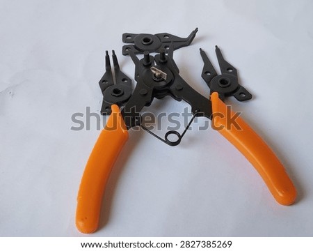 Four in one snap ring pliers with interchangeable tips and orange handles isolated on a white background